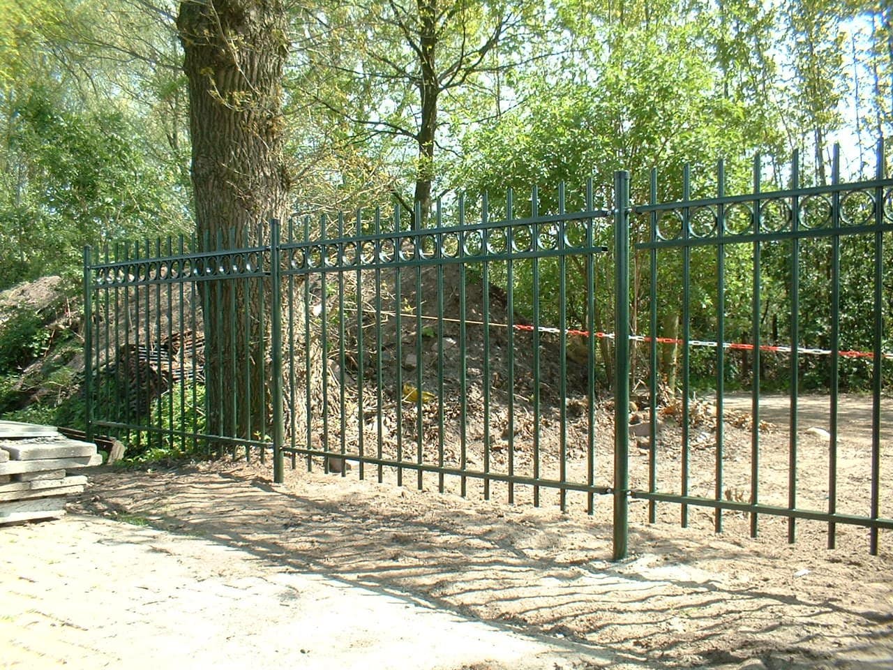 Hoog spijlenhekwerk rond een erf
